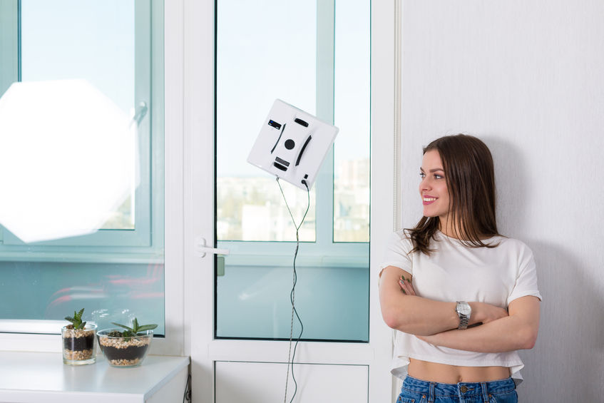 76498822 - woman cleaning windows at home with robotic cleaner